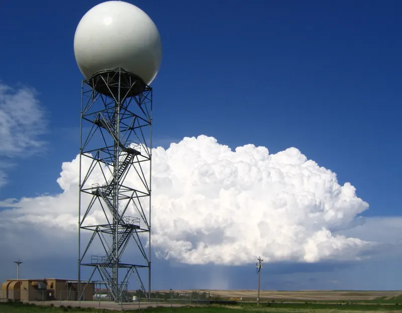 A weather radar radome standing in front of a storm cloud