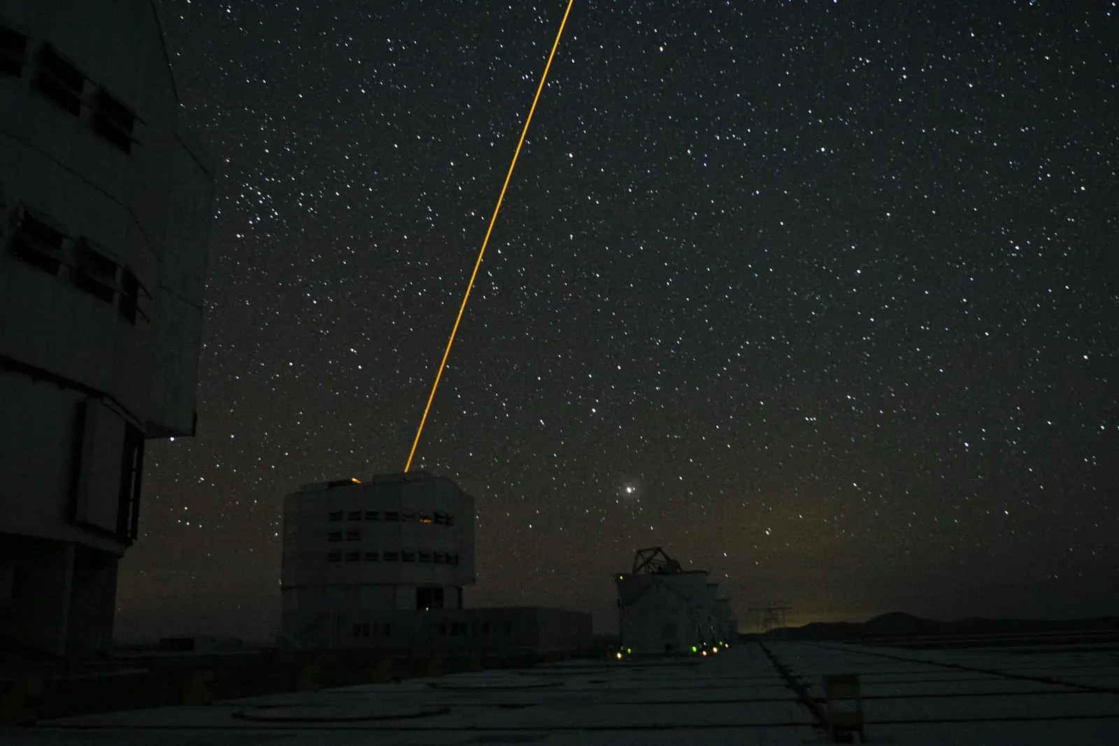 A laser guide star crossing the night sky above the Paranal observatory